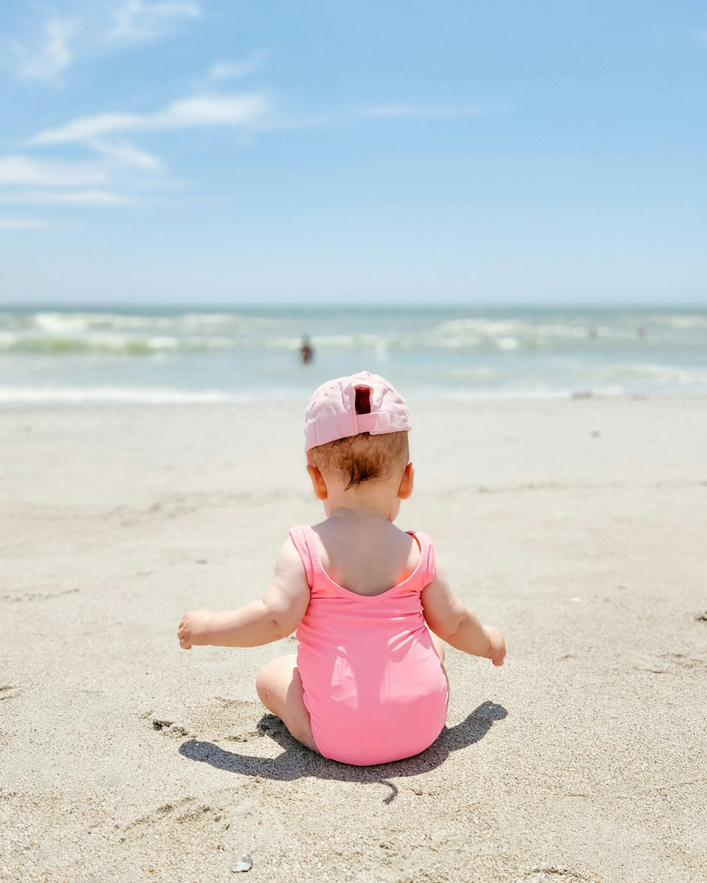 a baby in a pink swimsuit on a beach