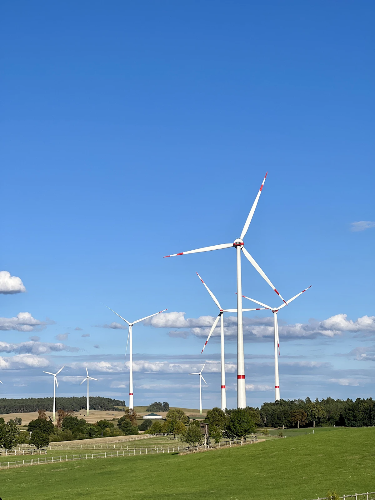 Aerial view of wind turbines standing across green farmland under heavy cloud