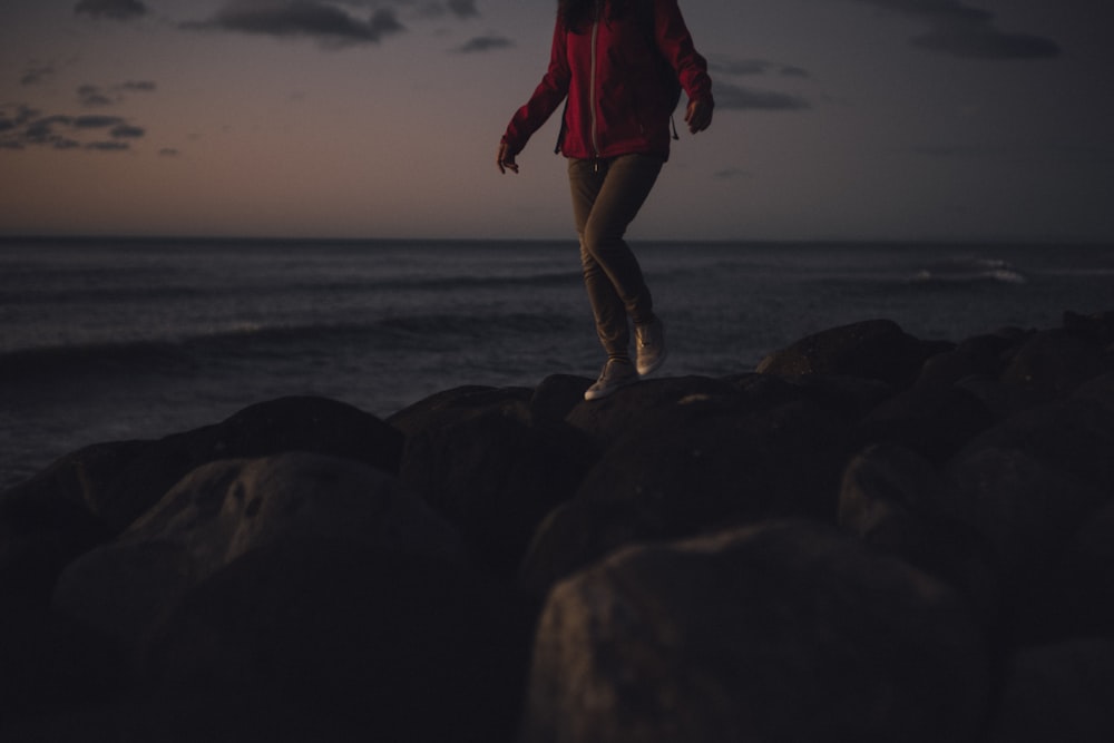 a person walking on rocks by the water