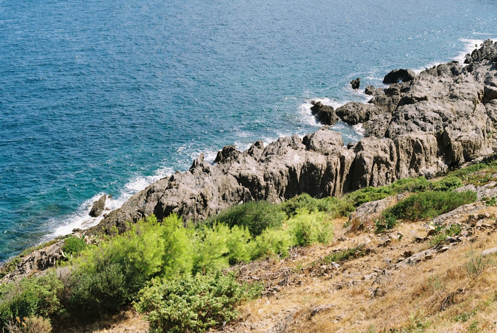 a rocky cliff next to a body of water