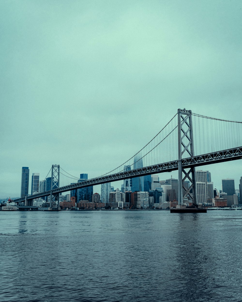 a bridge over water with a city in the background