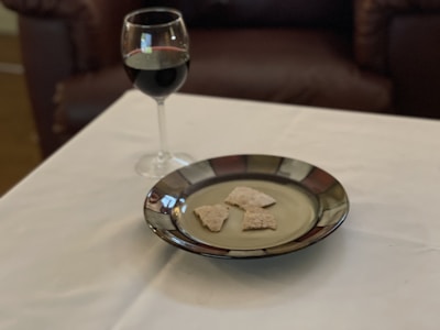 Elegant glass of red wine beside a plate of assorted tapas on a softly lit table.