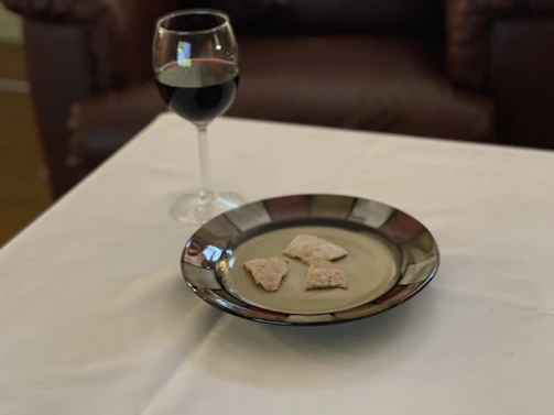 A glass of red wine next to a dish of gourmet tapas on a wooden table.