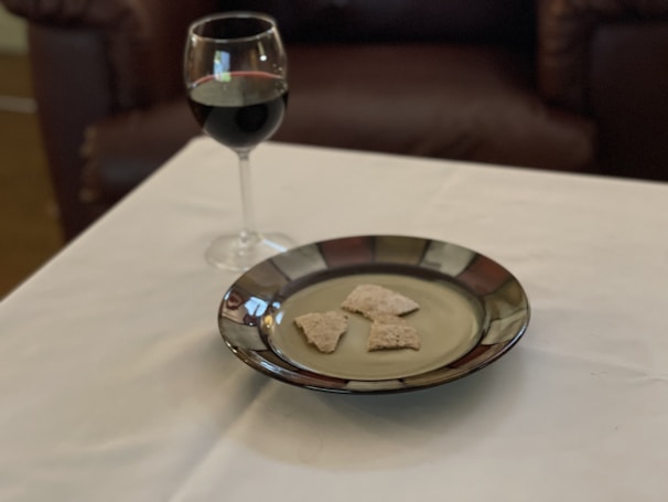 A cozy café table with a glass of Bulgarian red wine and a small plate of lyutenitsa spread.