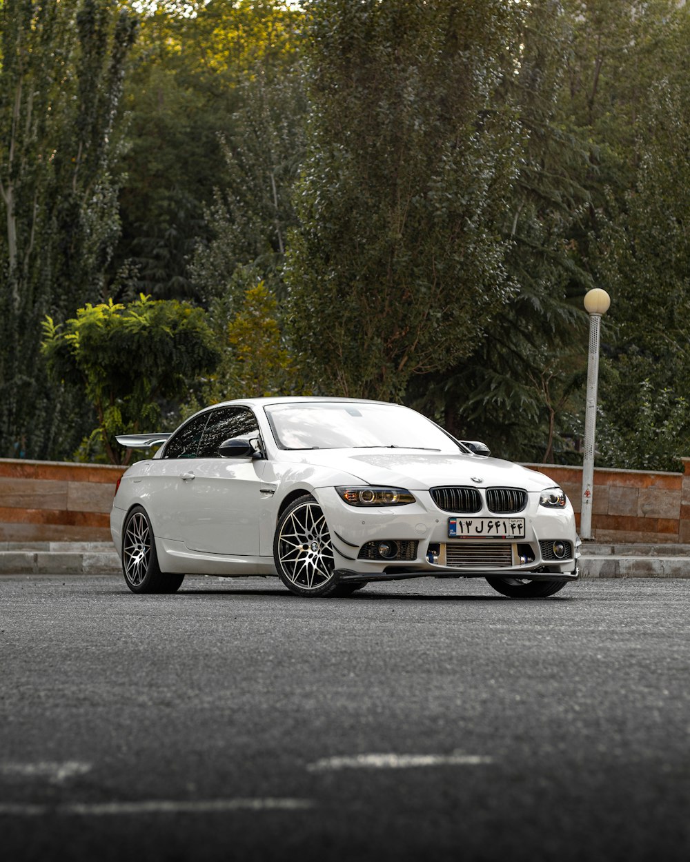 a white sports car parked on a street with trees in the background