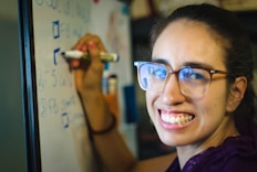 a person smiling and holding a marker