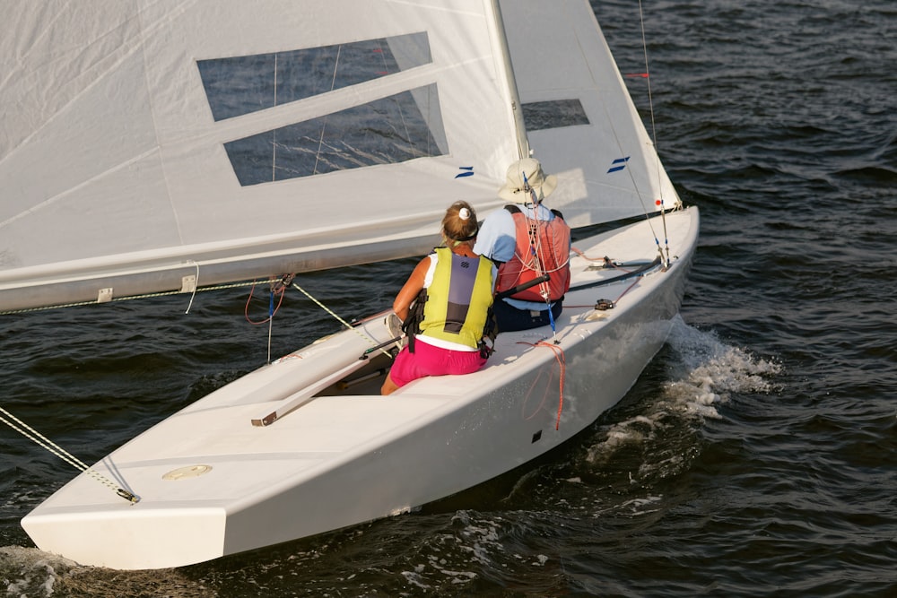 a couple of people on a sailboat in the water