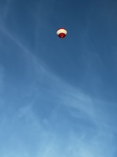 A high-altitude weather balloon floating against a clear blue sky with the clouds research logo visible.