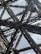 Intricate metallic structures form an elaborate network of beams and girders, creating an architectural design with geometric patterns. The beams appear sturdy and are set against a backdrop of a cloudy sky.
