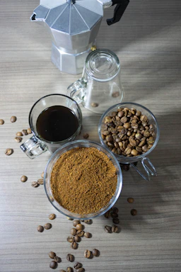 A rustic wooden table with assorted coffee products including roasted beans, ground coffee, and a steaming cup of coffee.