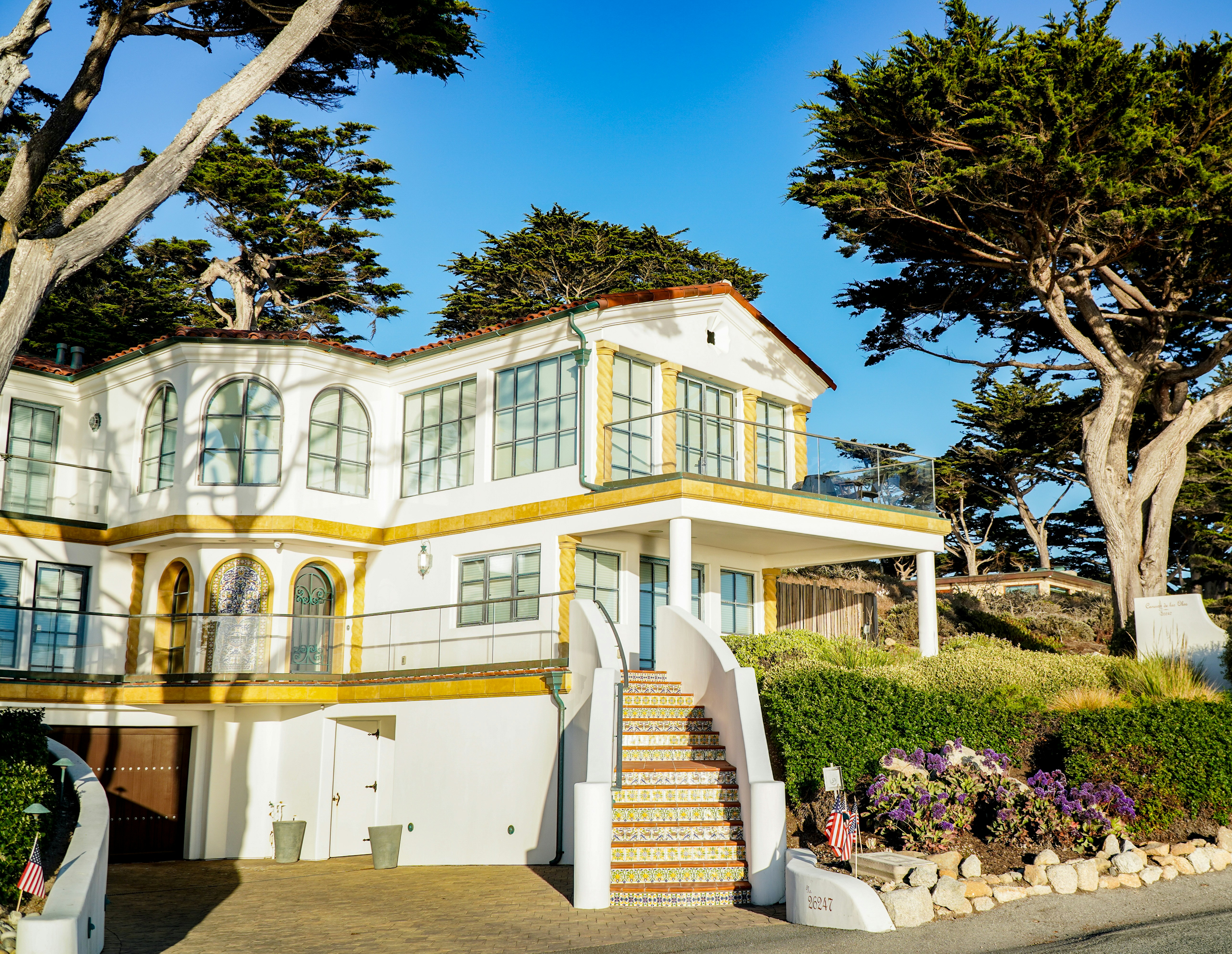 a large white house with trees and bushes around it
