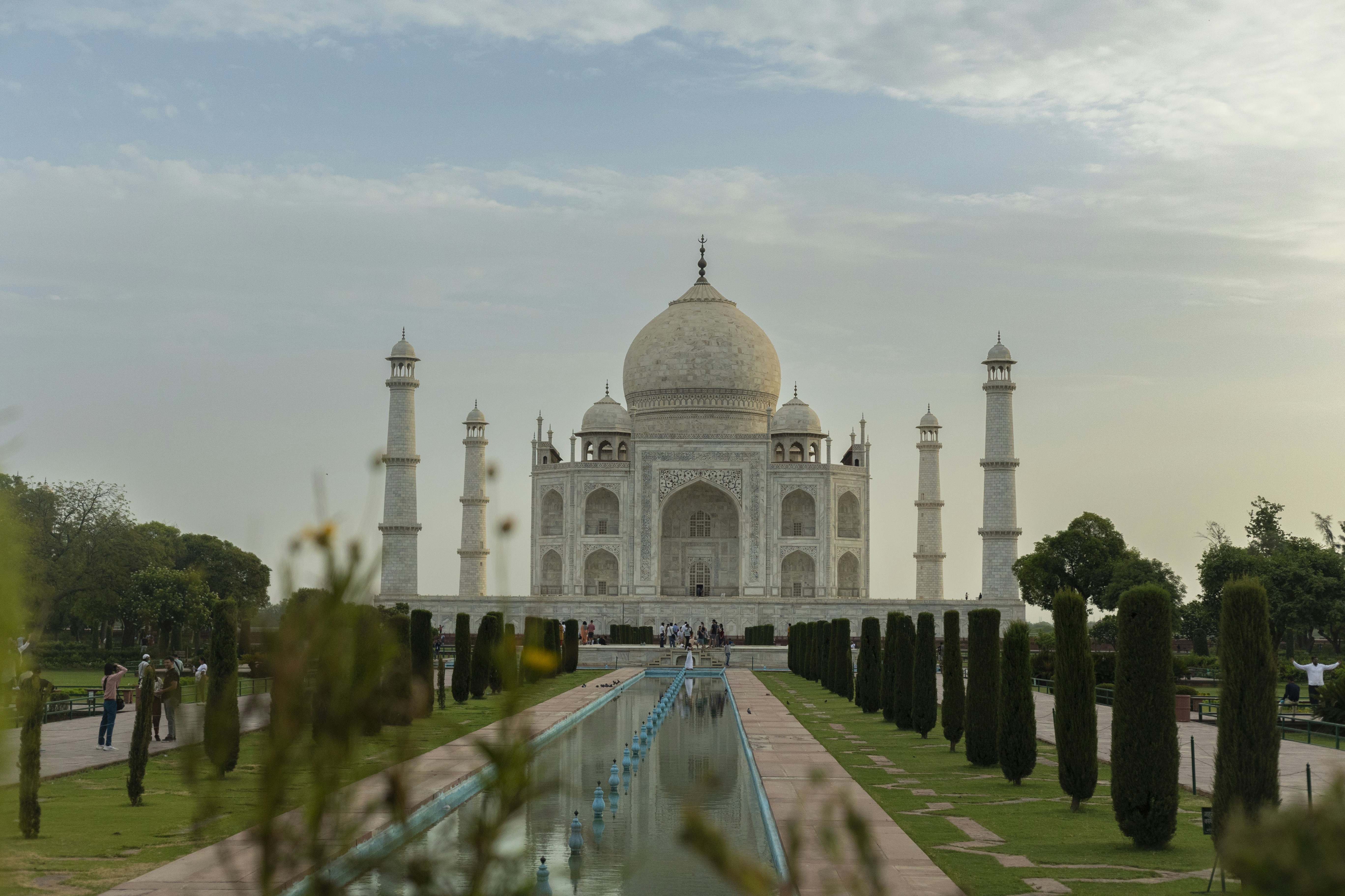 a large white building with a dome and towers with Taj Mahal in the background
