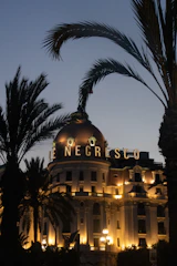 Exclusive balcony overlooking the Monaco Grand Prix track at dusk, bathed in burgundy and gold hues.