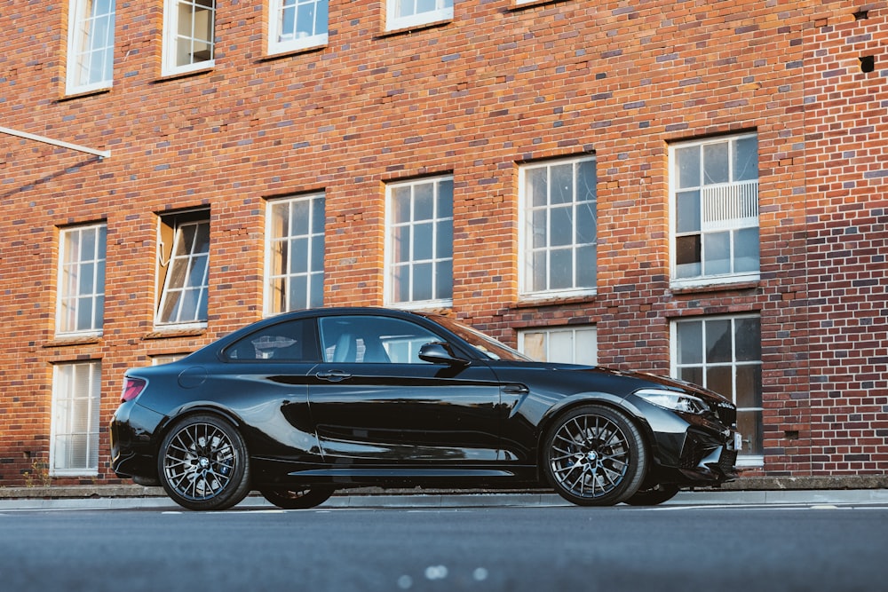 a black sports car parked in front of a brick building