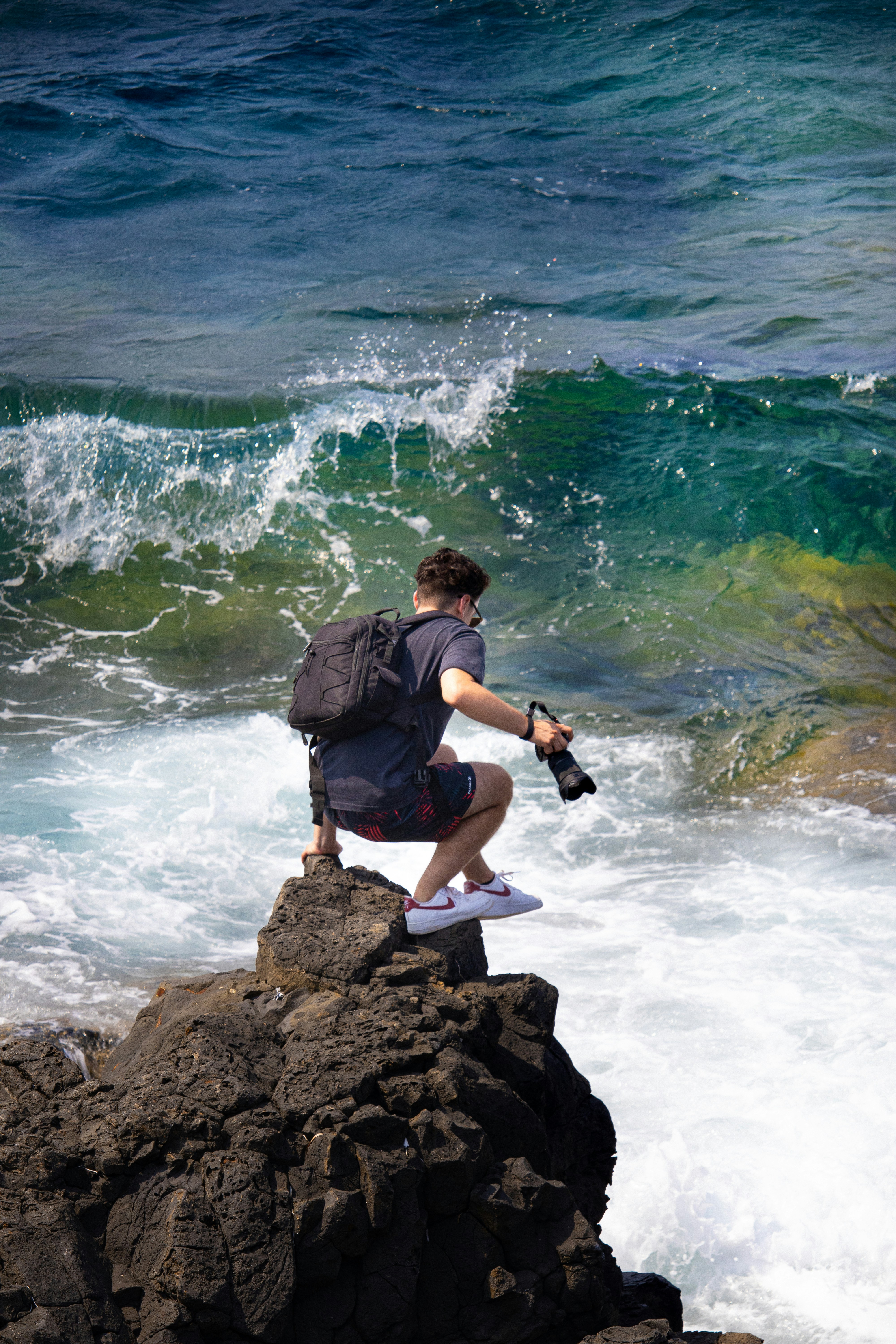 a man sitting on a rock looking at the ocean
