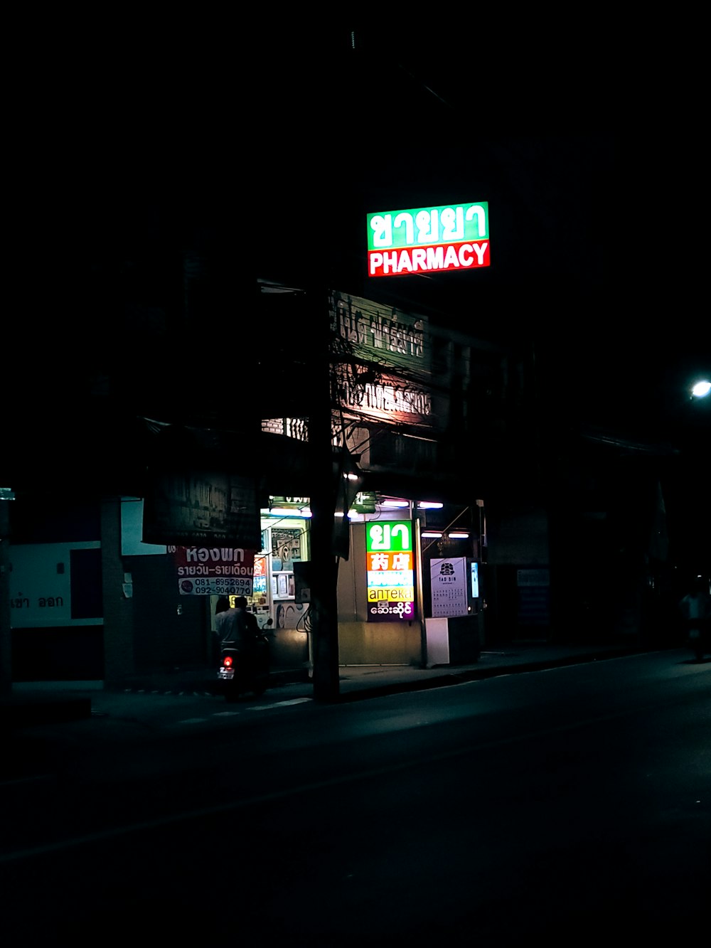 a person standing outside a building with neon signs at night