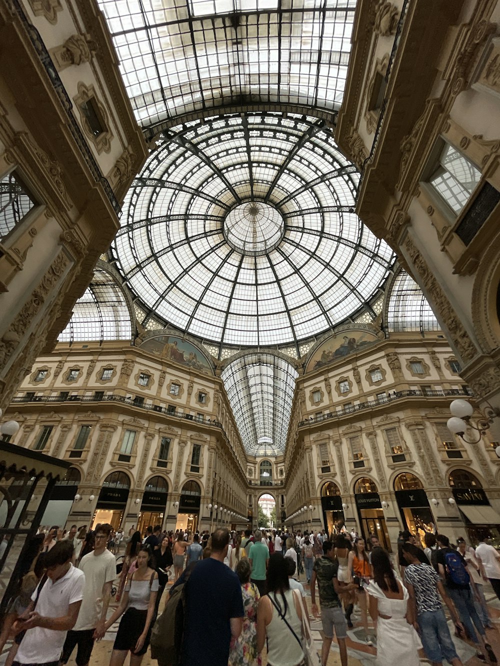 un folto gruppo di persone all'interno di un grande edificio con la Galleria Vittorio Emanuele II sullo sfondo