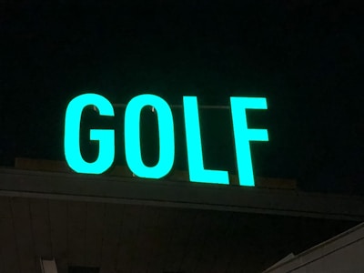 A brightly lit sign displaying the word 'GOLF' in large, green letters. The background is dark, suggesting the photo was taken at night.