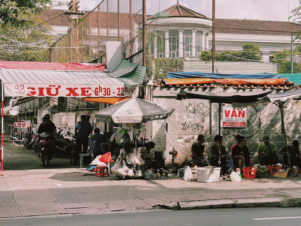 a group of individuals sit outside a small shop