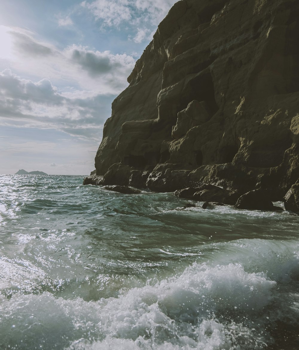 a rocky cliff with waves crashing against it