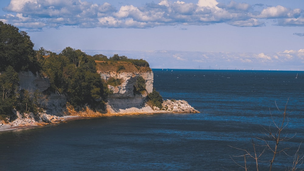 a rocky island with trees and blue water