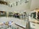 A multi-level indoor shopping mall with people walking along a corridor on an upper floor. There are several shops with closed shutters and a fast-food restaurant sign visible. The floor is tiled, and the area is well illuminated with ceiling lights.
