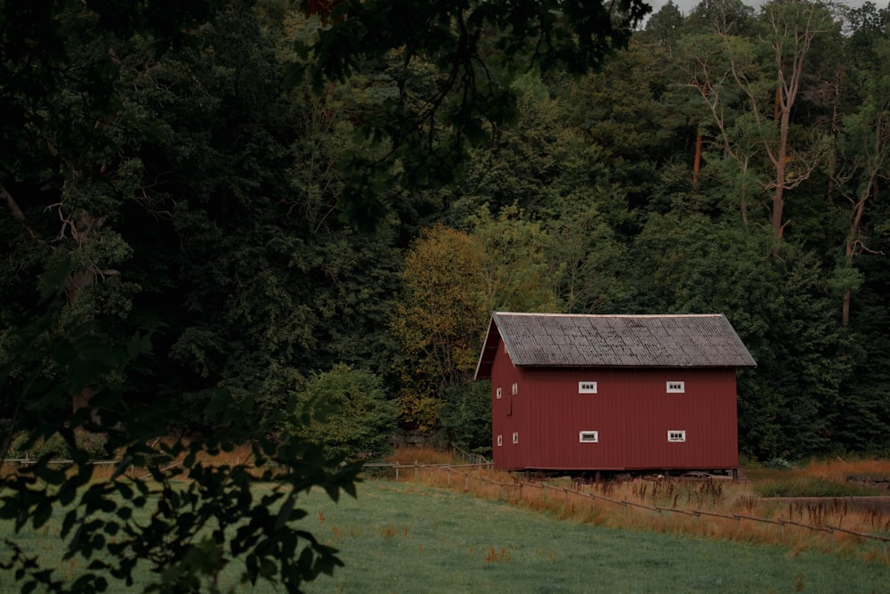 a red barn next to a forest