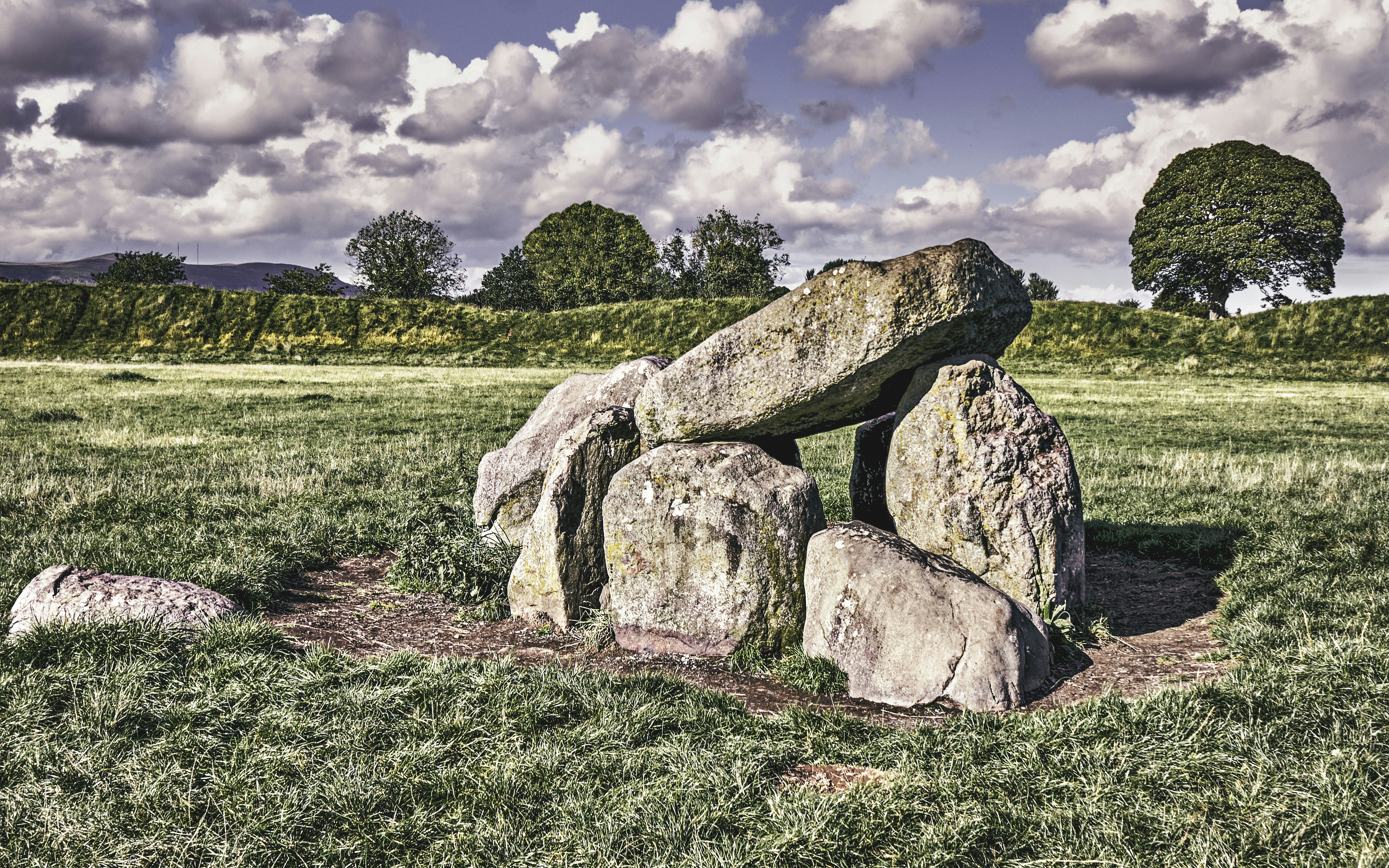 a group of men sitting on a rock in the middle of a field