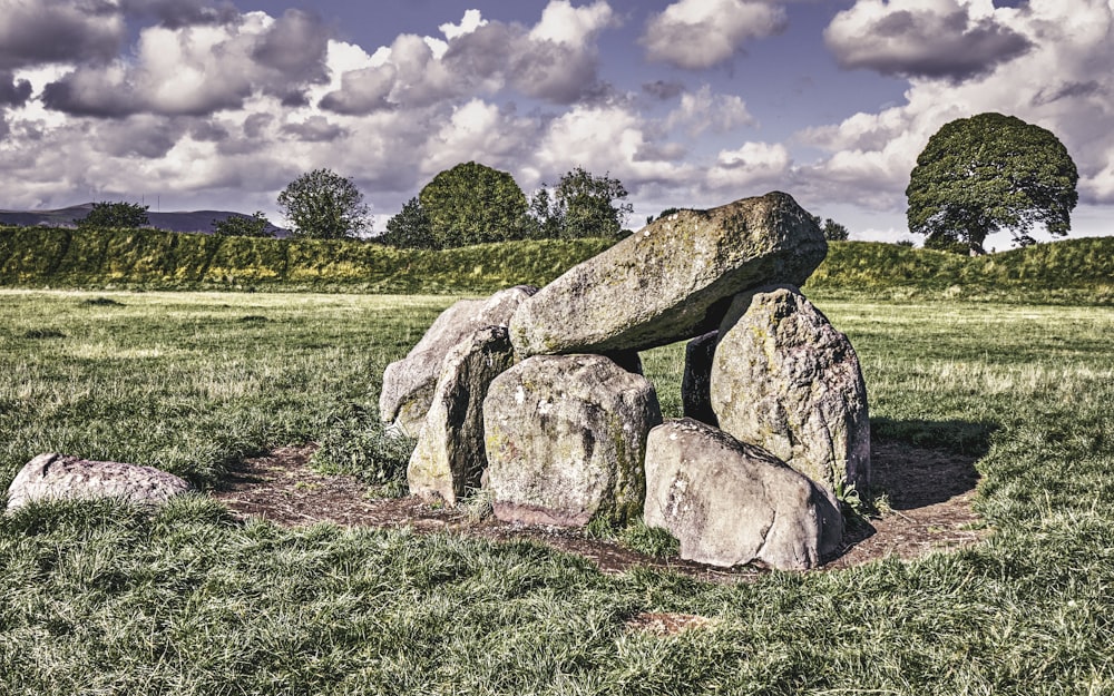 a group of men sitting on a rock in the middle of a field