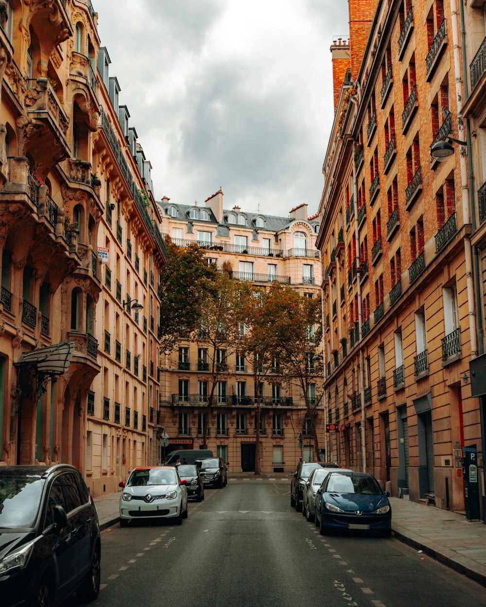 a narrow city street with cars parked on the side of a building