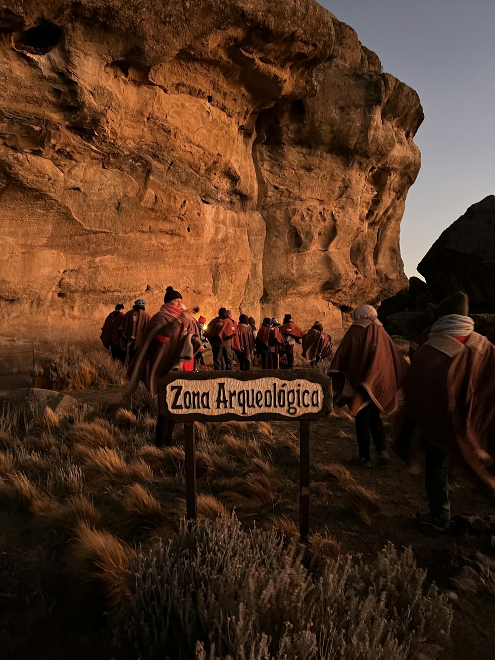 a group of people walking on a path between a rocky cliff