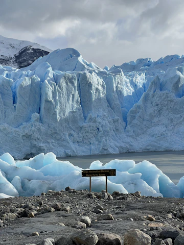 a sign in front of a glacier with Perito Moreno Glacier in the background
