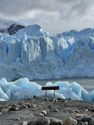 a sign in front of a glacier with Perito Moreno Glacier in the background