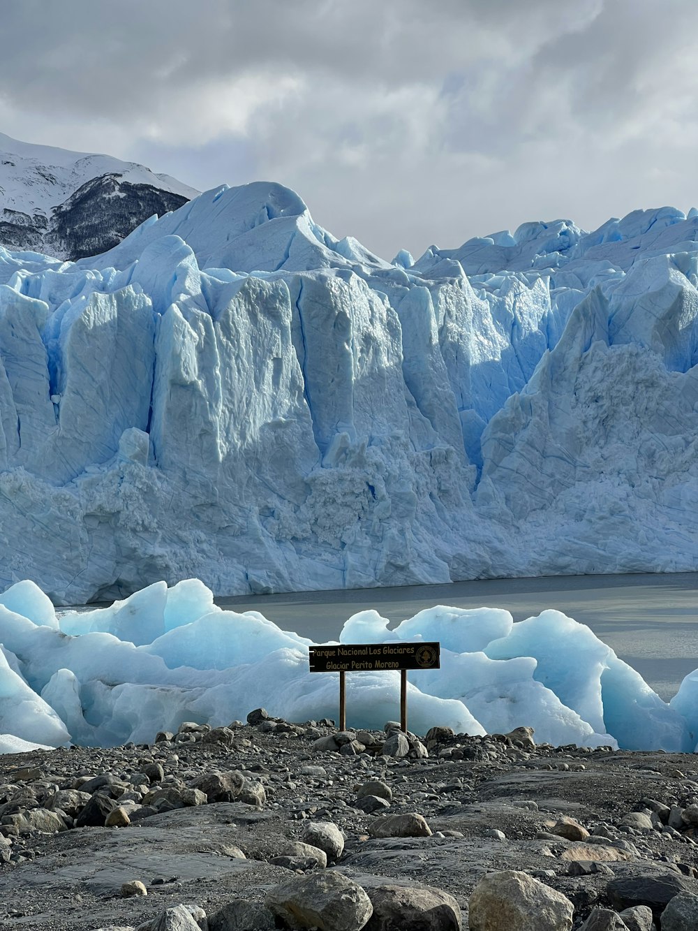 a sign in front of a glacier with Perito Moreno Glacier in the background