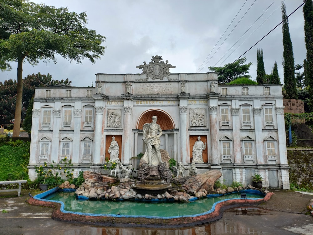 a white building with statues and a fountain in front of it