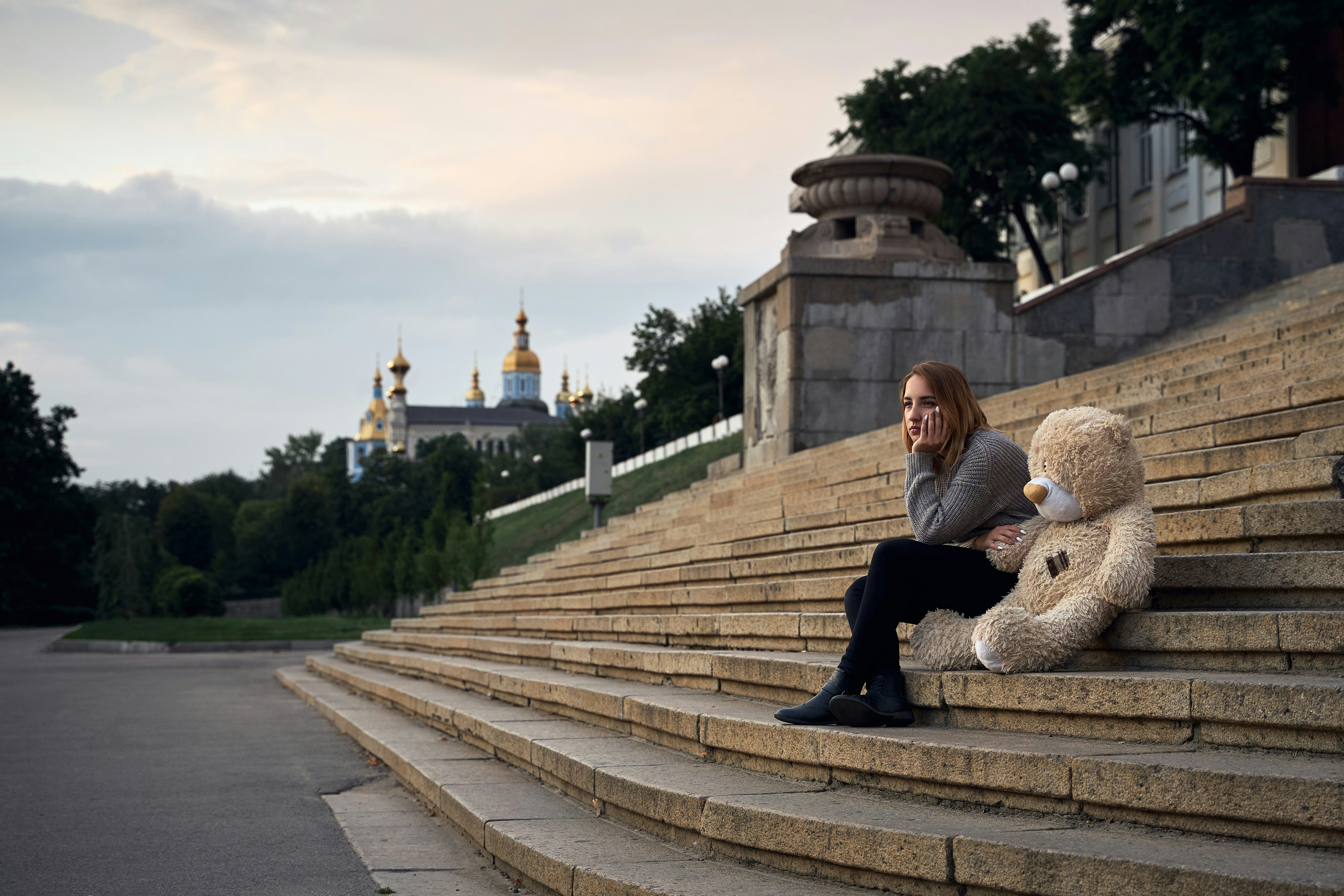 a person sitting on a stone staircase with a teddy bear