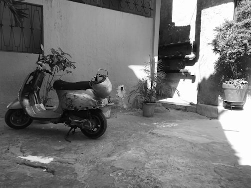 A vintage Siambretta motorcycle parked beside a rustic workshop with tools hanging on the wall.