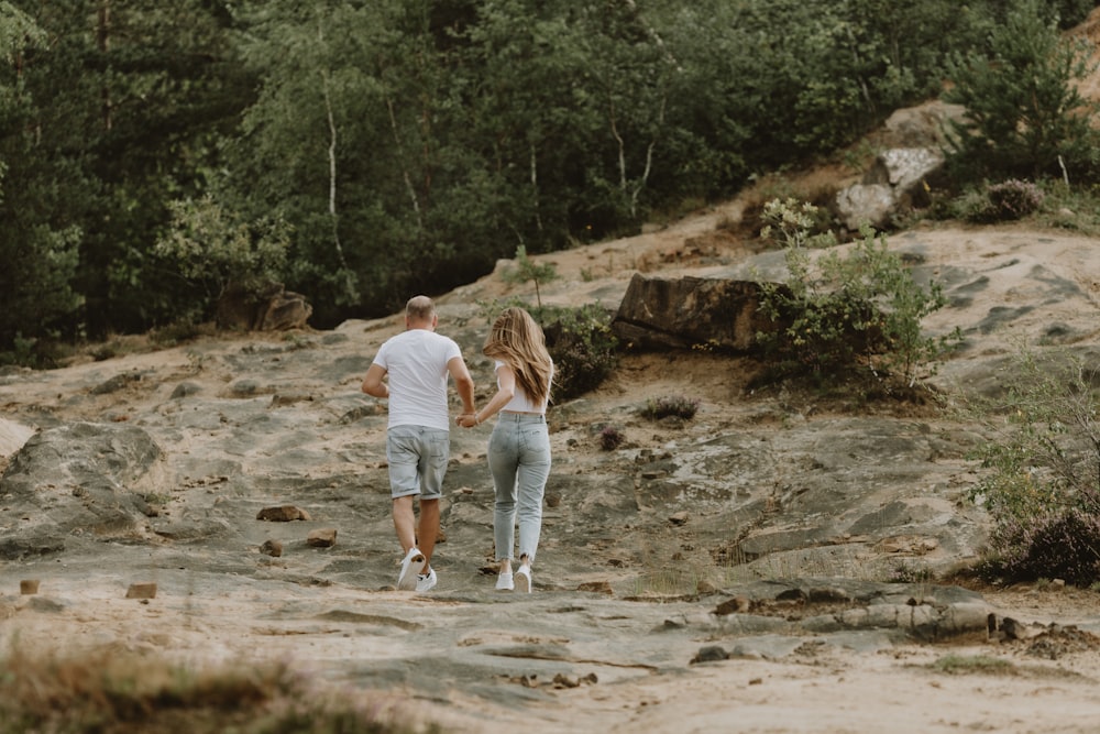 a man and woman walking on a dirt path in the woods