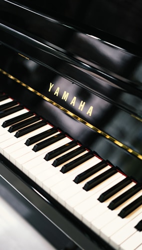 A close-up of a Yamaha piano keyboard showcasing the black and white keys with a glossy finish. The brand name 'Yamaha' is prominently displayed above the keys.