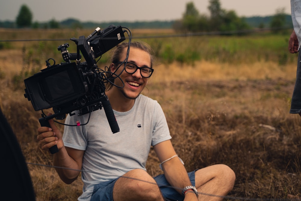 a man sitting on a chair with a camera on his shoulder