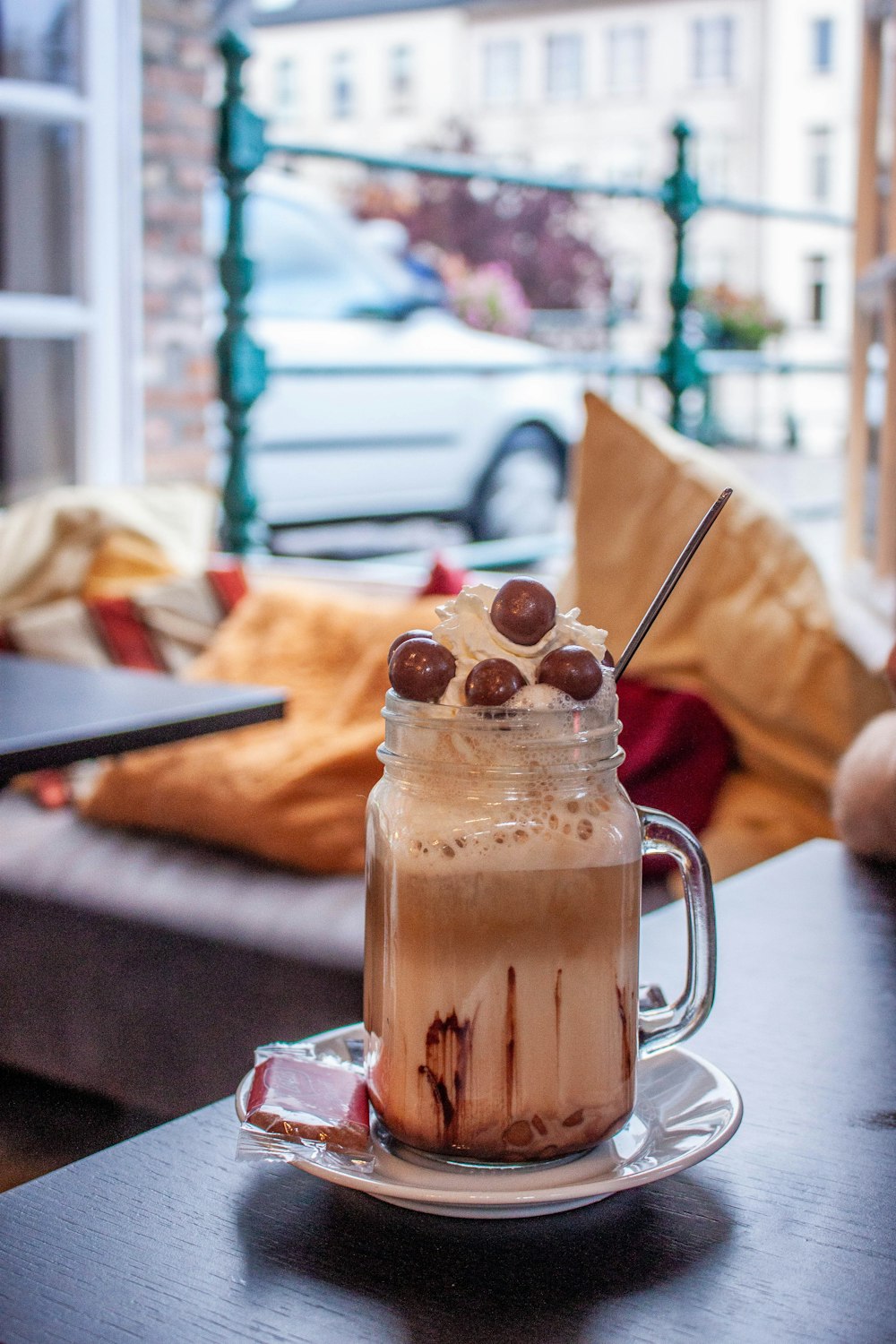 a glass of brown liquid with ice and fruit on a table