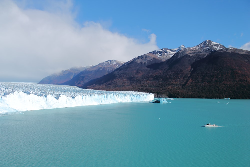 a body of water with a glacier and mountains in the background