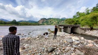 Field scientists collecting water samples beside a winding river.