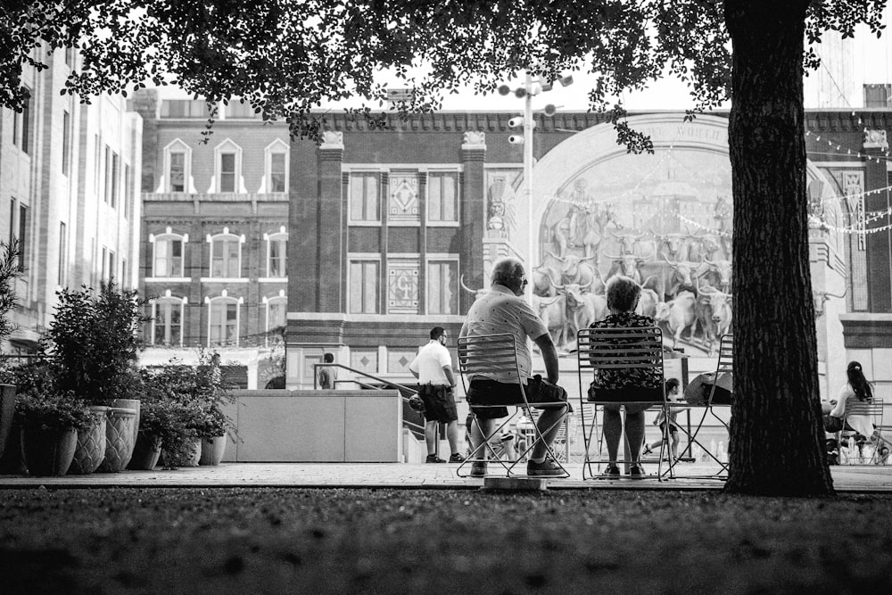 a group of people sitting on a bench in front of a large building