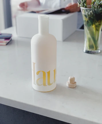 Sleek glass bottles branded with a luxury hotel logo displayed on a marble countertop.