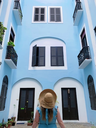 a person sitting on a sidewalk looking at a building with windows