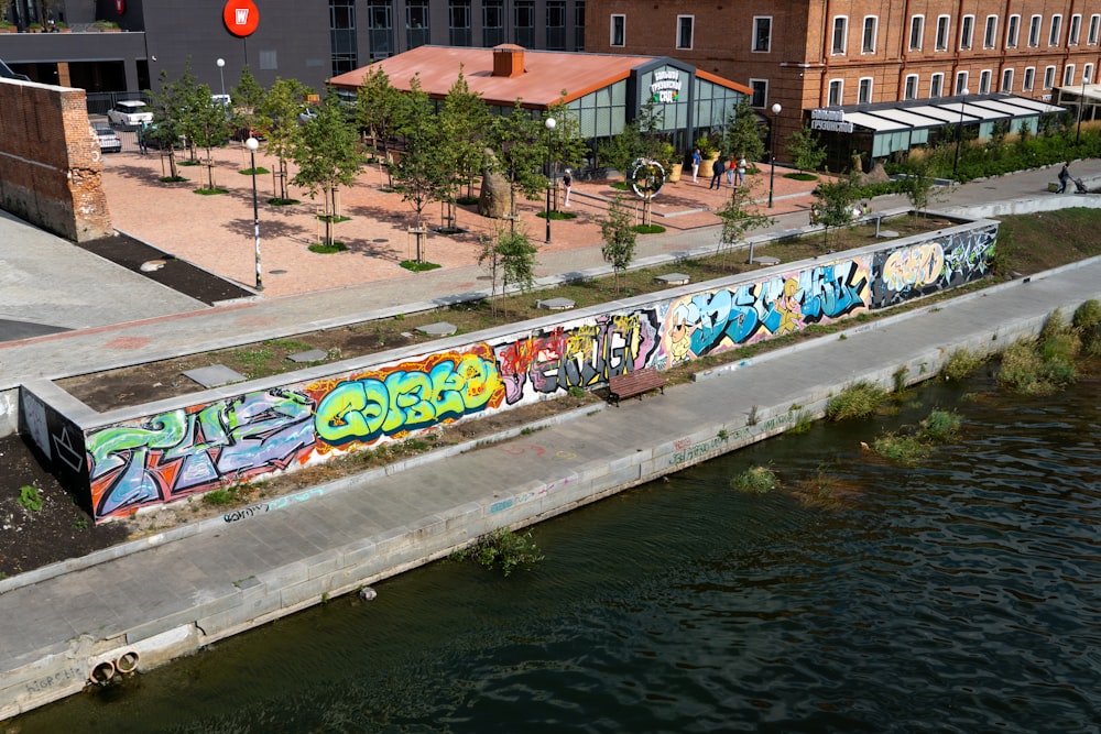 a body of water with a wall with graffiti on it