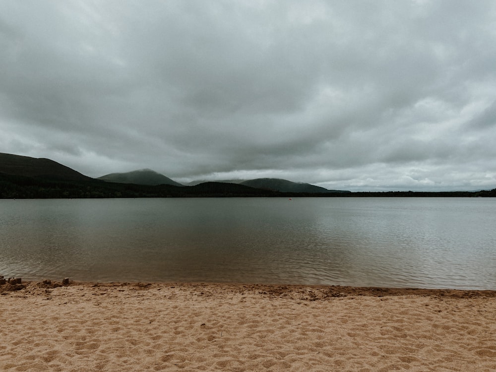 a beach with a body of water and mountains in the background