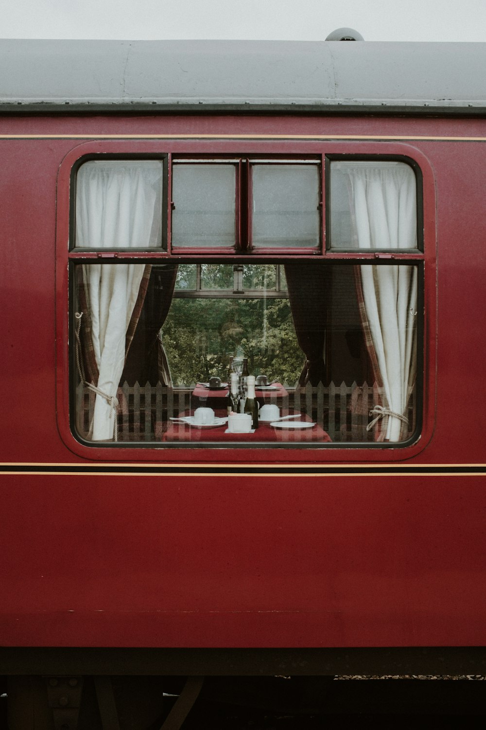 a red train with a table and chairs in the window