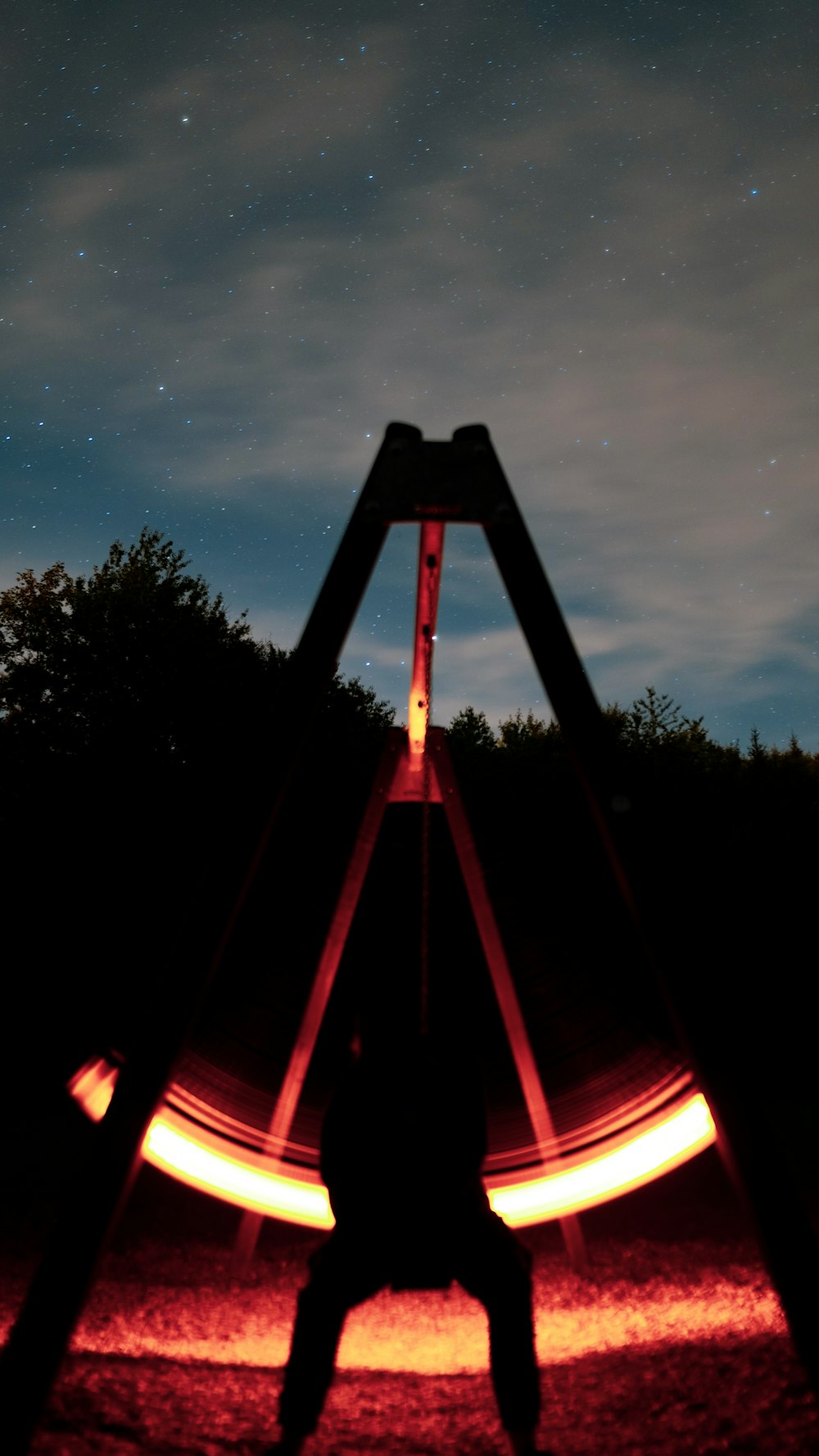 a silhouette of a person standing in front of a large metal structure